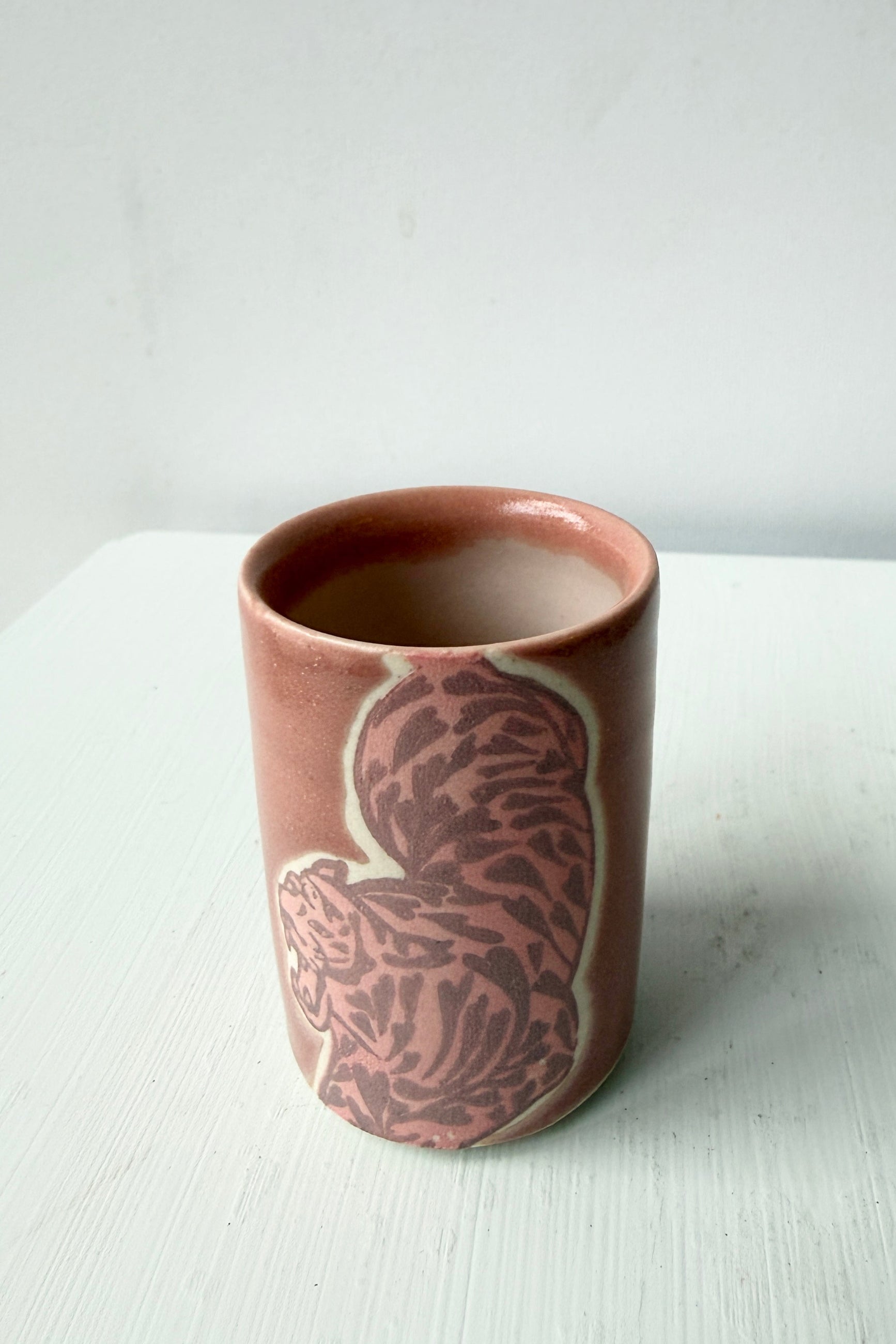 Ceramic mauve tiger cup with a decorative design on a white surface ©Sprout Home