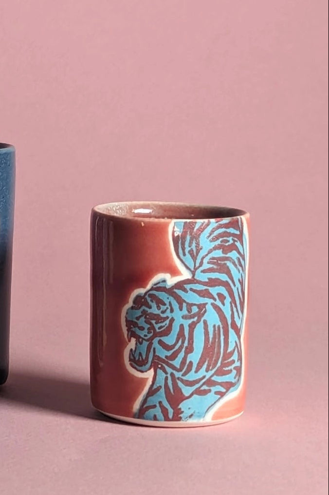ceramic cup in a red teal with animal patterns on a pink background ©City In Bloom Ceramics