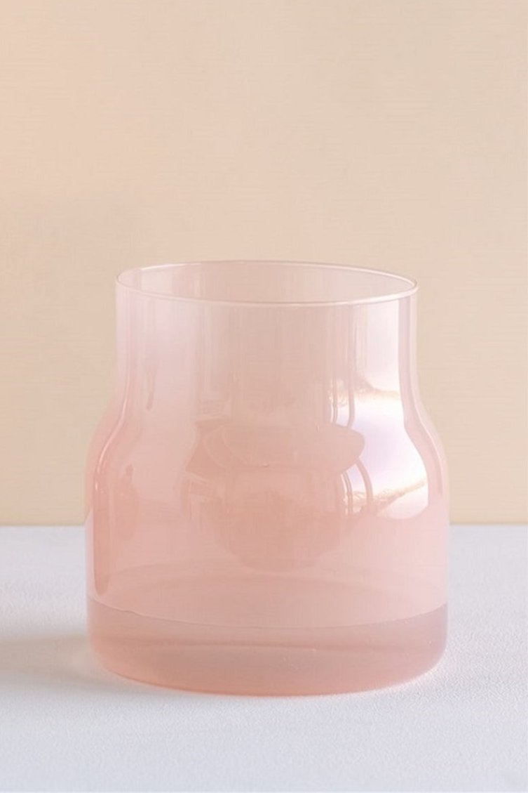 The Bodii vase against a peach background and white table highlighting the pink glass.