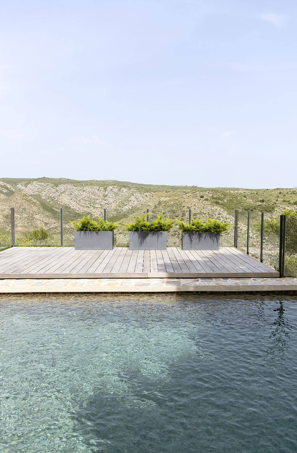 Wooden deck with Jort Grey Large planters by a pool with a mountainous landscape in the background ©Pottery Pots