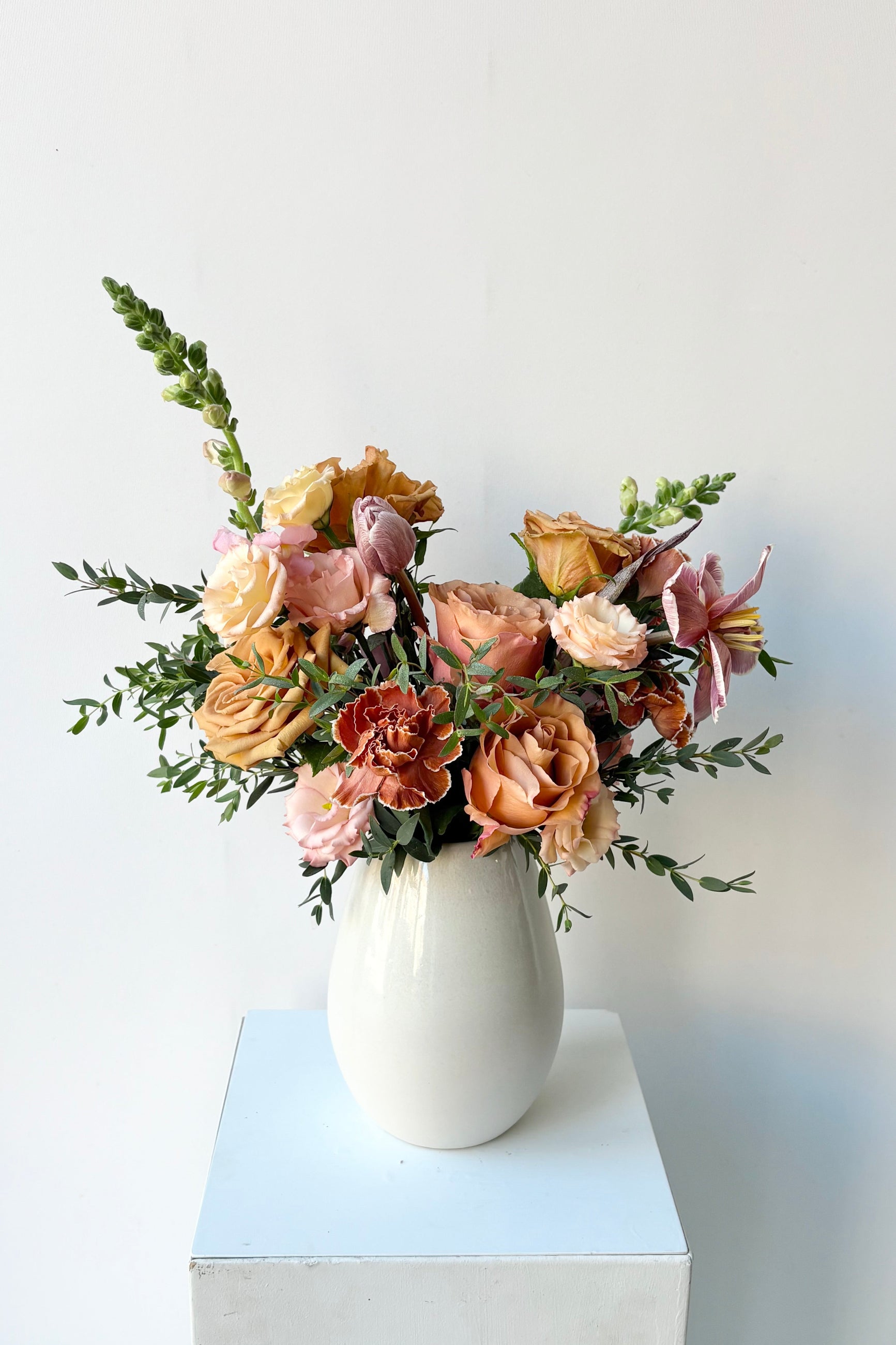 a Sprout Home custom floral arrangemenbt in a white vase with bronze and caramel colored flowers in late winter. ©Sprout Home  #size_$75