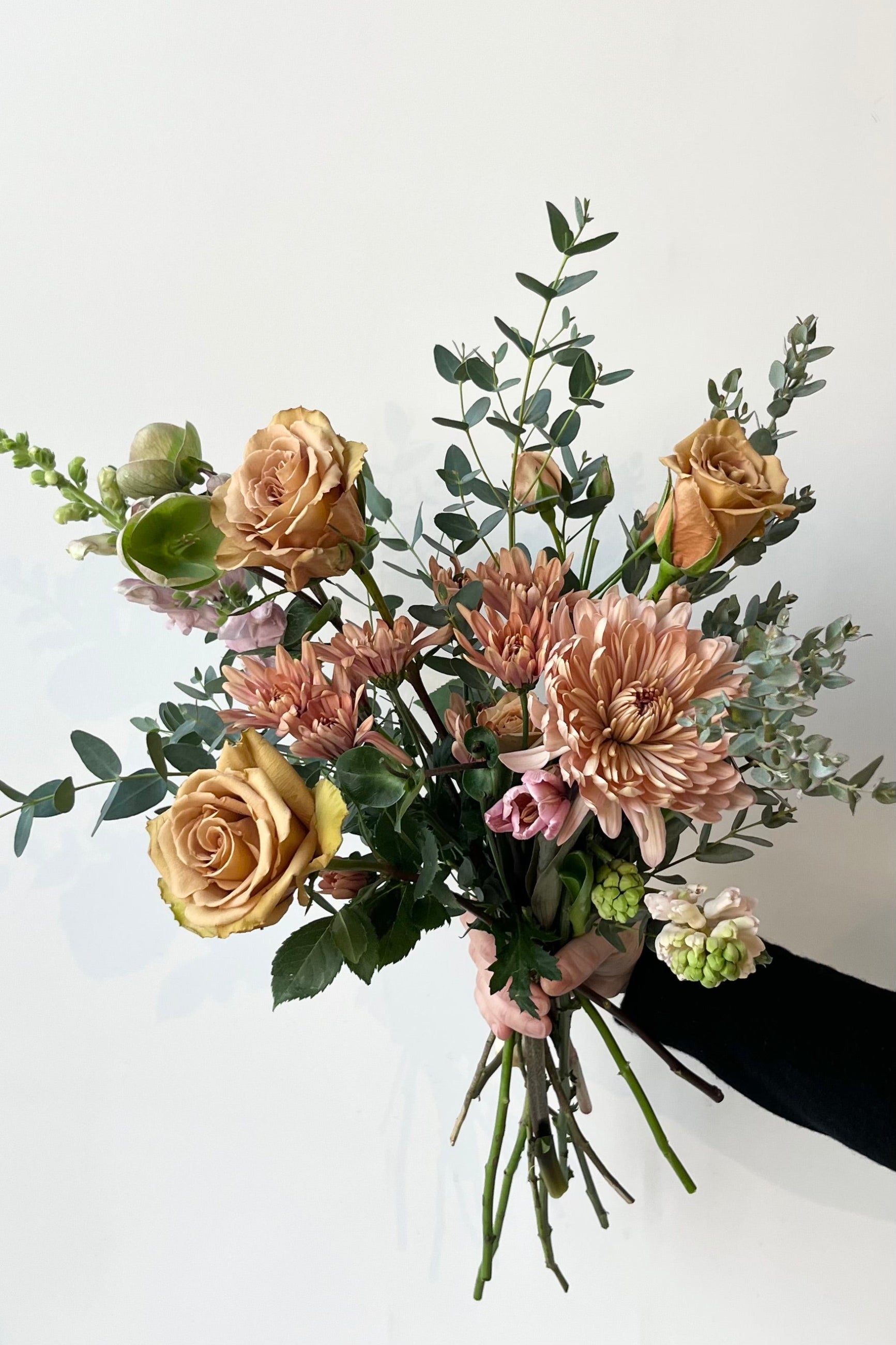 A sprout home bouquet of neutral toned flowers held in front of a white wall ©Sprout Home  #size_$75