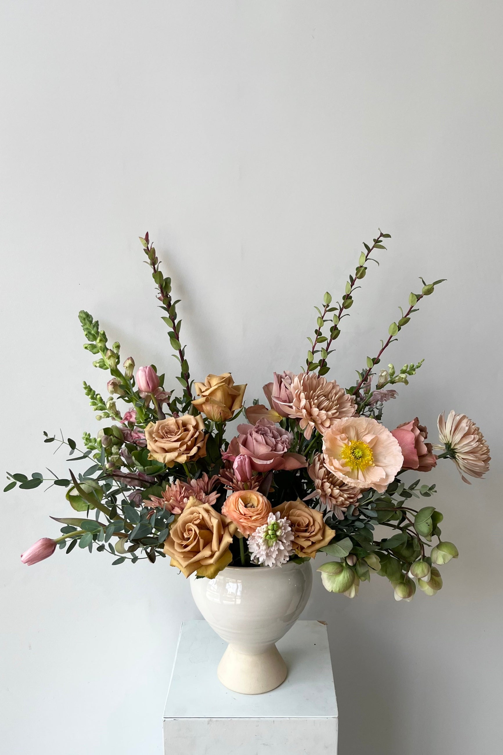 A Sprout Home floral arrangement in a white urn with dyed tulips and roses and poppies with warm neutral colors in late winter ©Sprout Home #size_$200