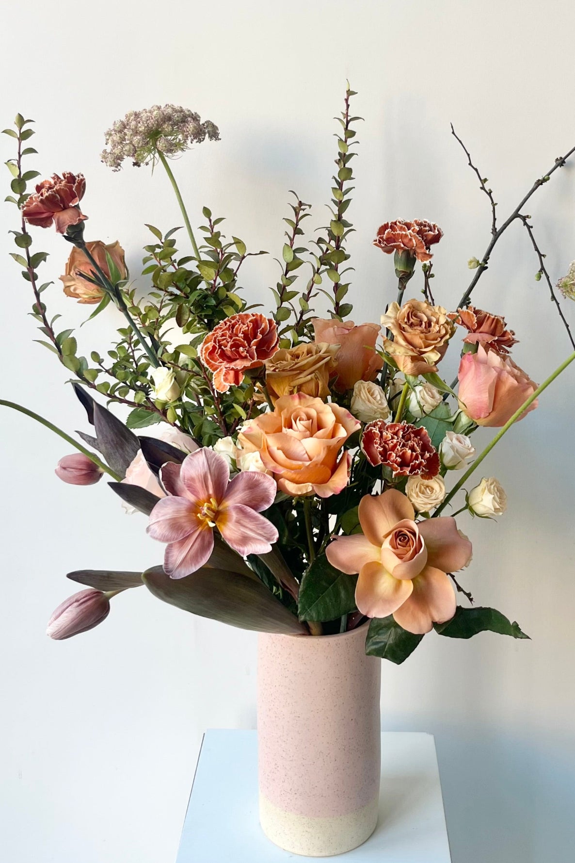 A Sprout Home floral arrangement in a pink vase with dyed tulips and roses and warm neutral colors in late winter ©Sprout Home #size_$160