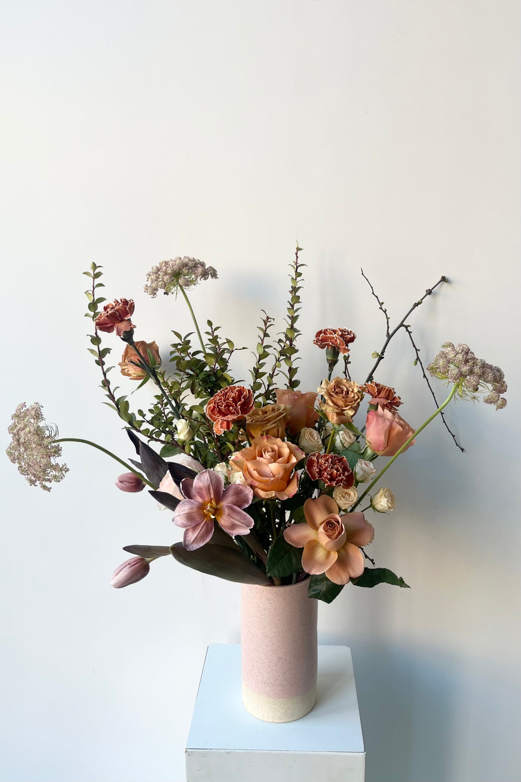 A Sprout Home floral arrangement in a white vase with dyed tulips and roses with warm neutral colors in late winter ©Sprout Home #size_$160