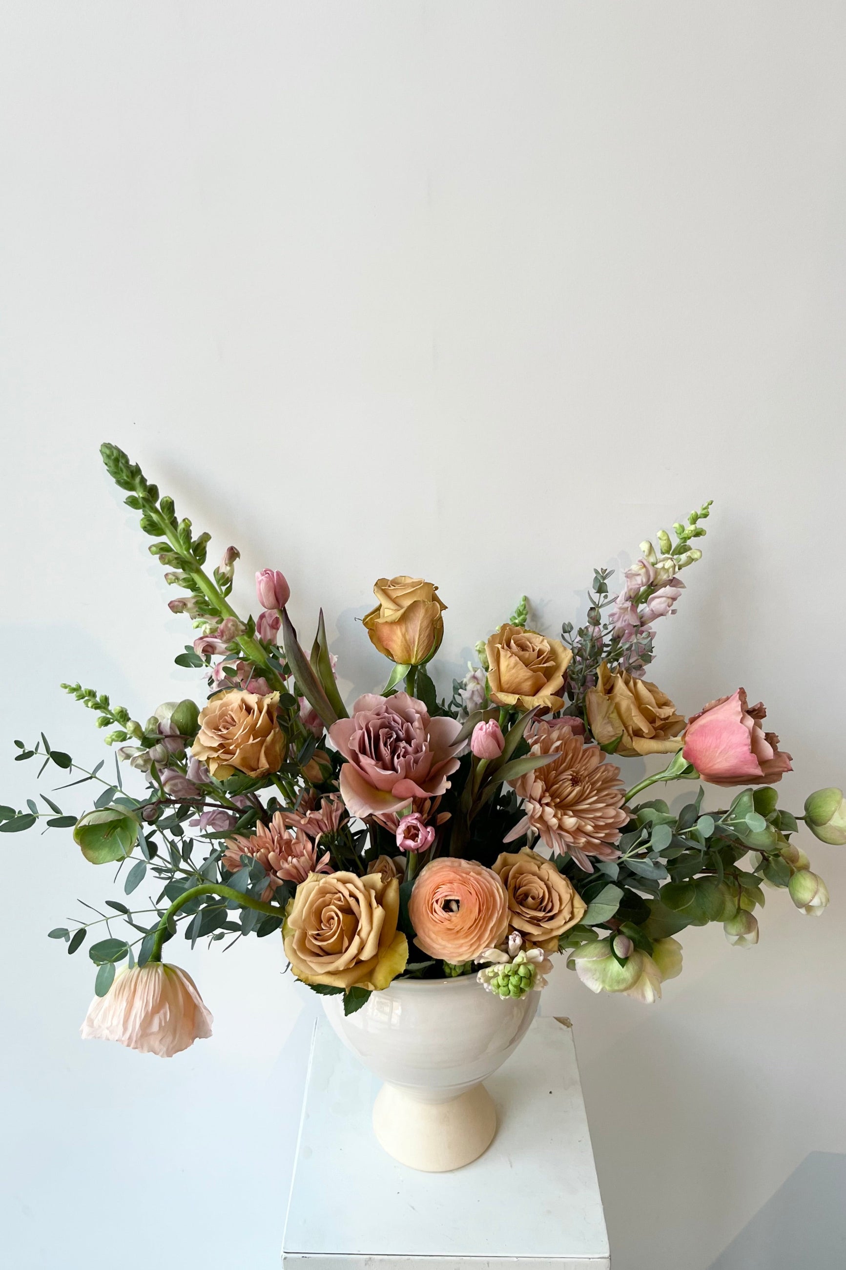 A Sprout Home floral arrangement in a white vase with roses ranunculus and poppies warm neutral colors in late winter ©Sprout Home #size_$160