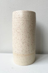 Cream Speckle Jacqueline vase Small against a white wall. 