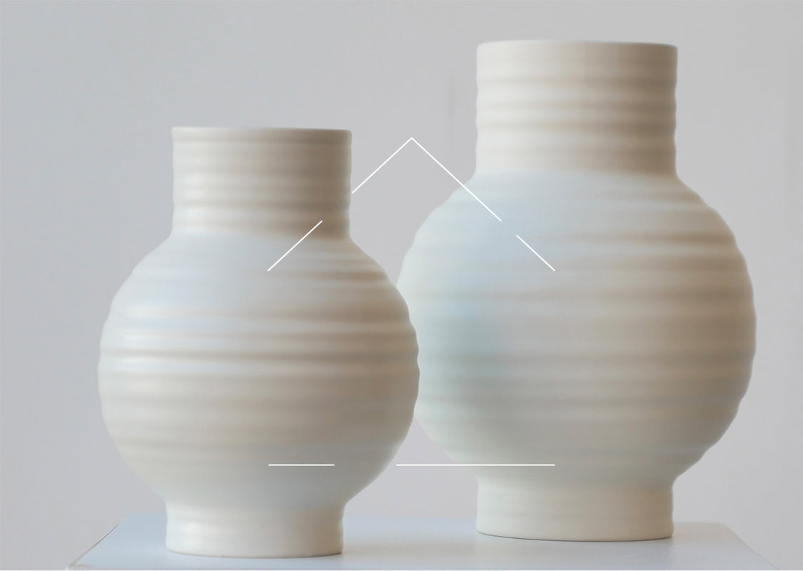 Two white ribbed vases against and white wall