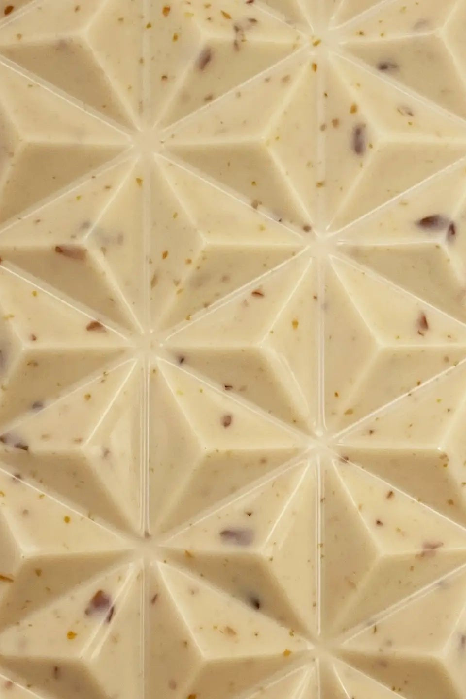 Photo of a Deux Cranes Creme Brulee Chocolate bar  in front of a white background. White chocolate with cocoa nibs. A textured chocolate bar in front of a white background.