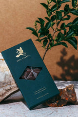 Photo of a Deux Cranes Dark Chocolate Miso Almond Bar positioned with natural elements like stone and branches.