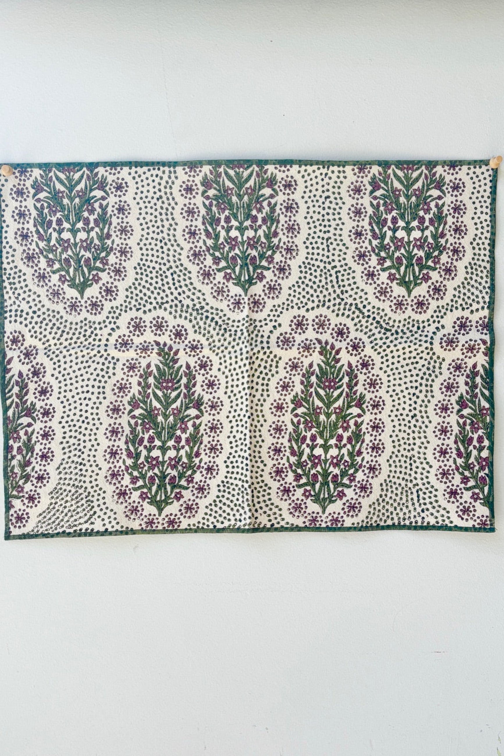 Hand-block-printed placemat on Khadi cotton and feature a floral and dot pattern in olive and saffron color displayed on a white surface ©Sprout Home