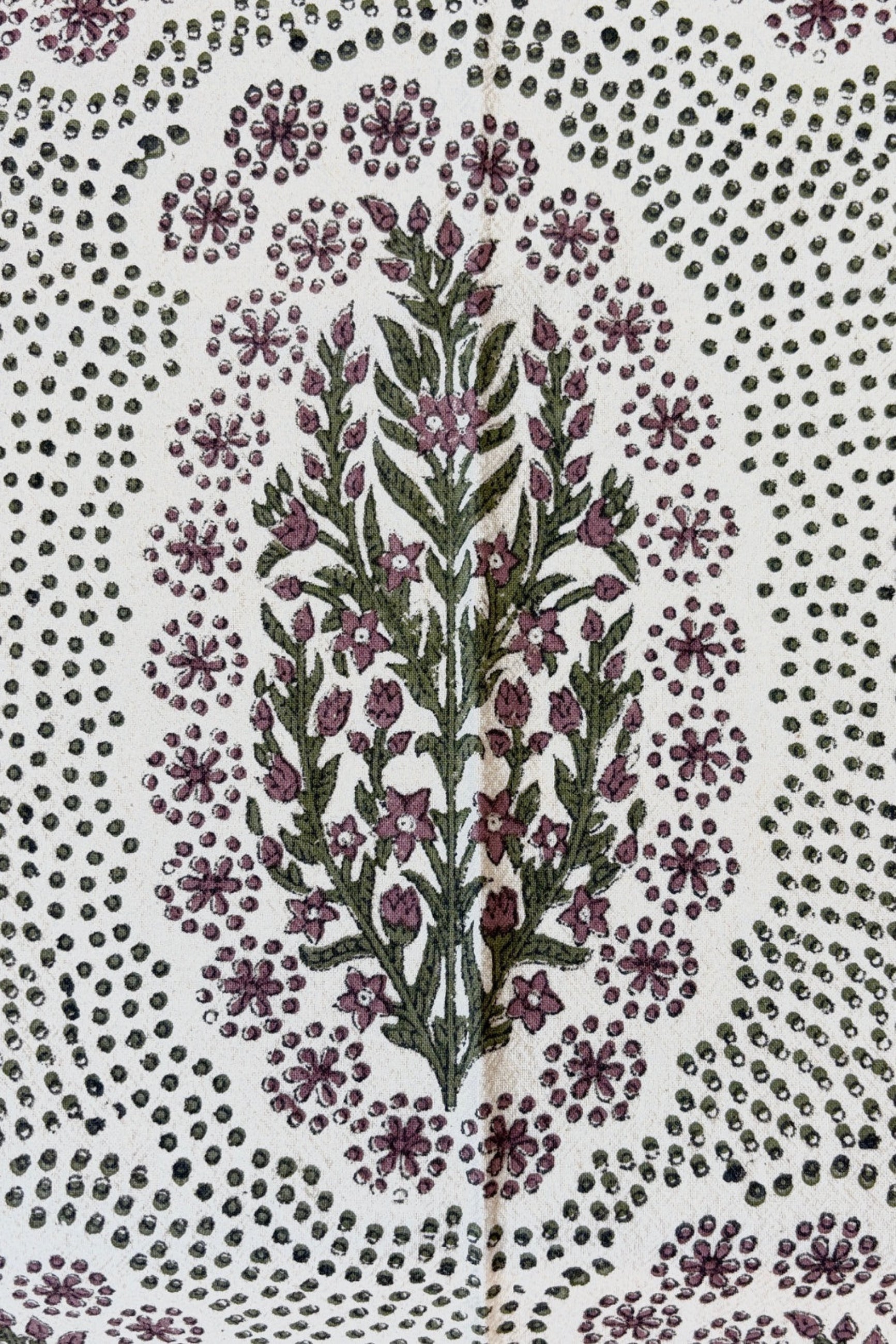 Close up of hand-block-printed placemat on Khadi cotton and feature a floral and dot pattern in olive and saffron color displayed on a white surface ©Sprout Home