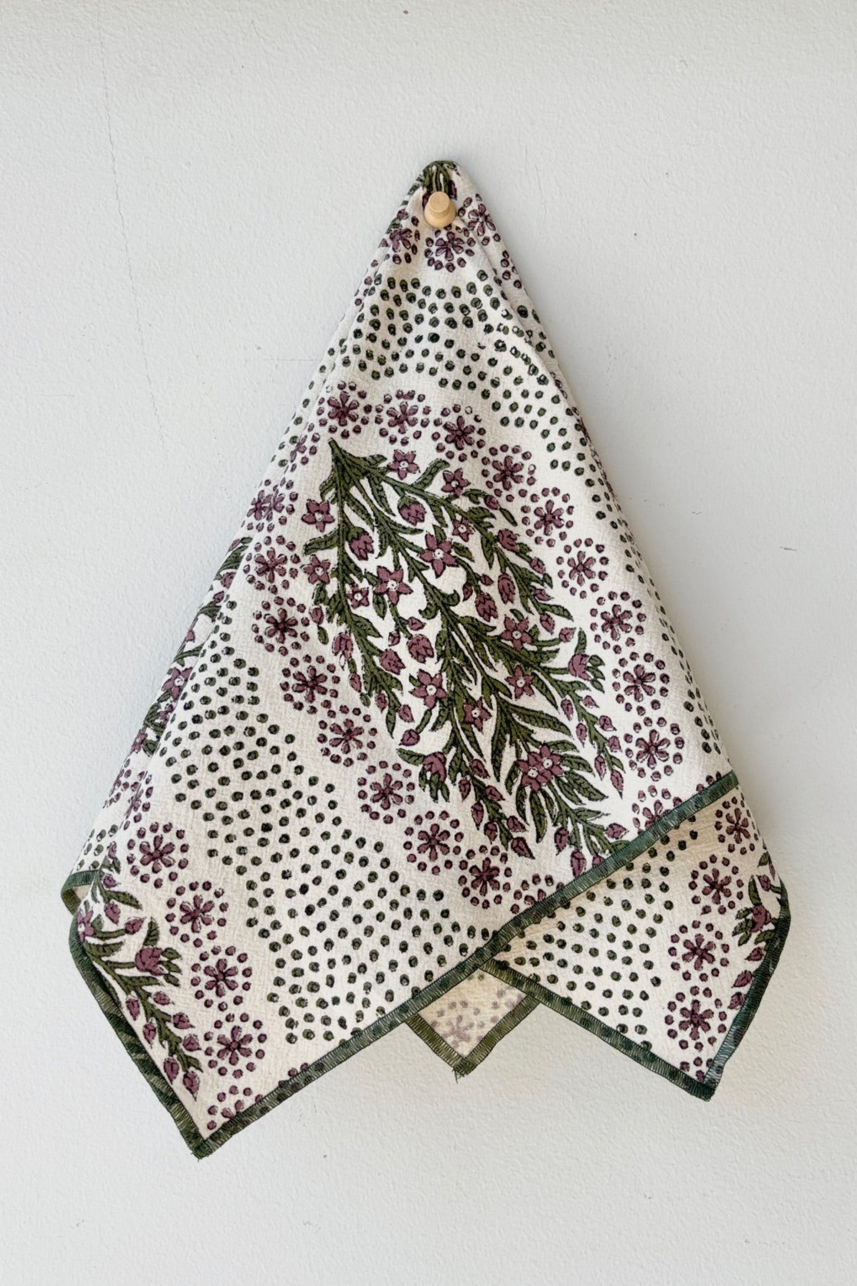 Hand-block-printed napkin on Khadi cotton with a floral and dot pattern in olive and saffron colors displayed on a white surface ©Sprout Home