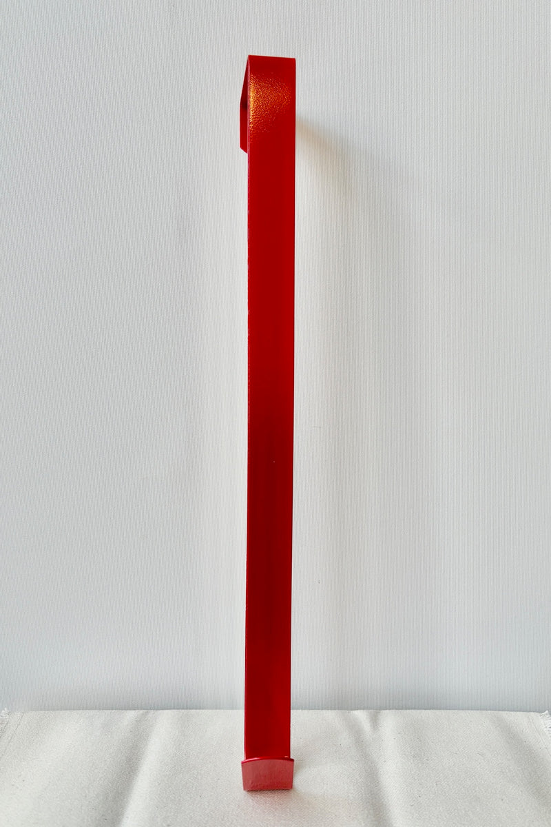 Simple wreath hanger in red against a white wall