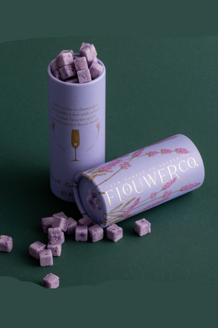 Purple cube-shaped candies in a 'Flouwerco' branded cylindrical container on a green background ©Flouwer Co.
