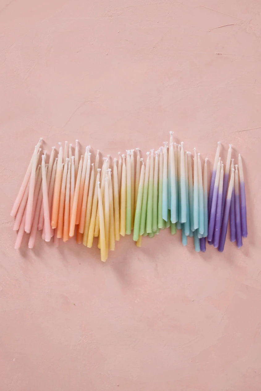 a group of Knot & Bow rainbow ombre short beeswax candles on pink