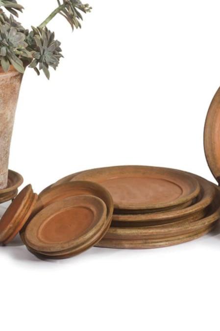 a grouping of various sized aged terracotta saucers on white backdrop