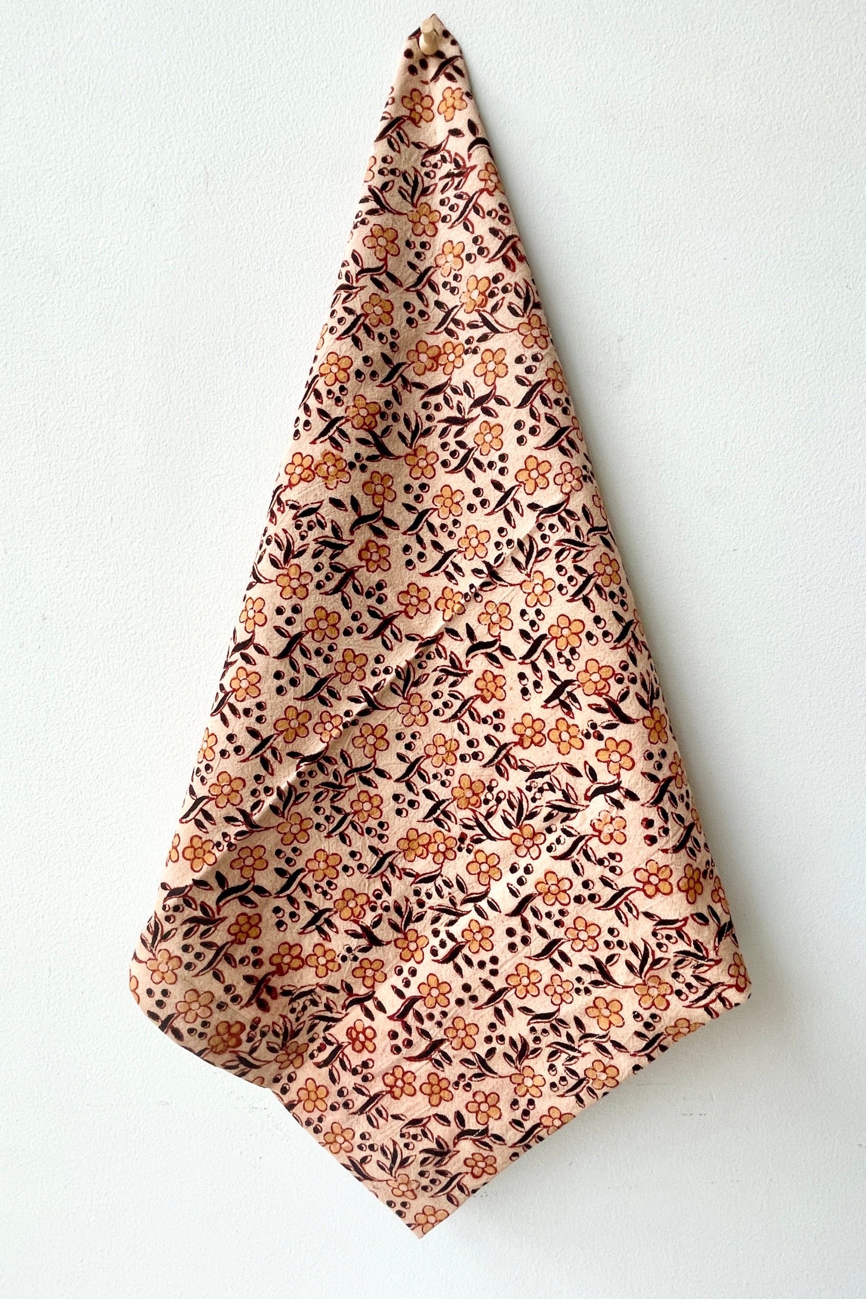 The Sao Anika napkin being held against a white wall.  ©Sprout Home