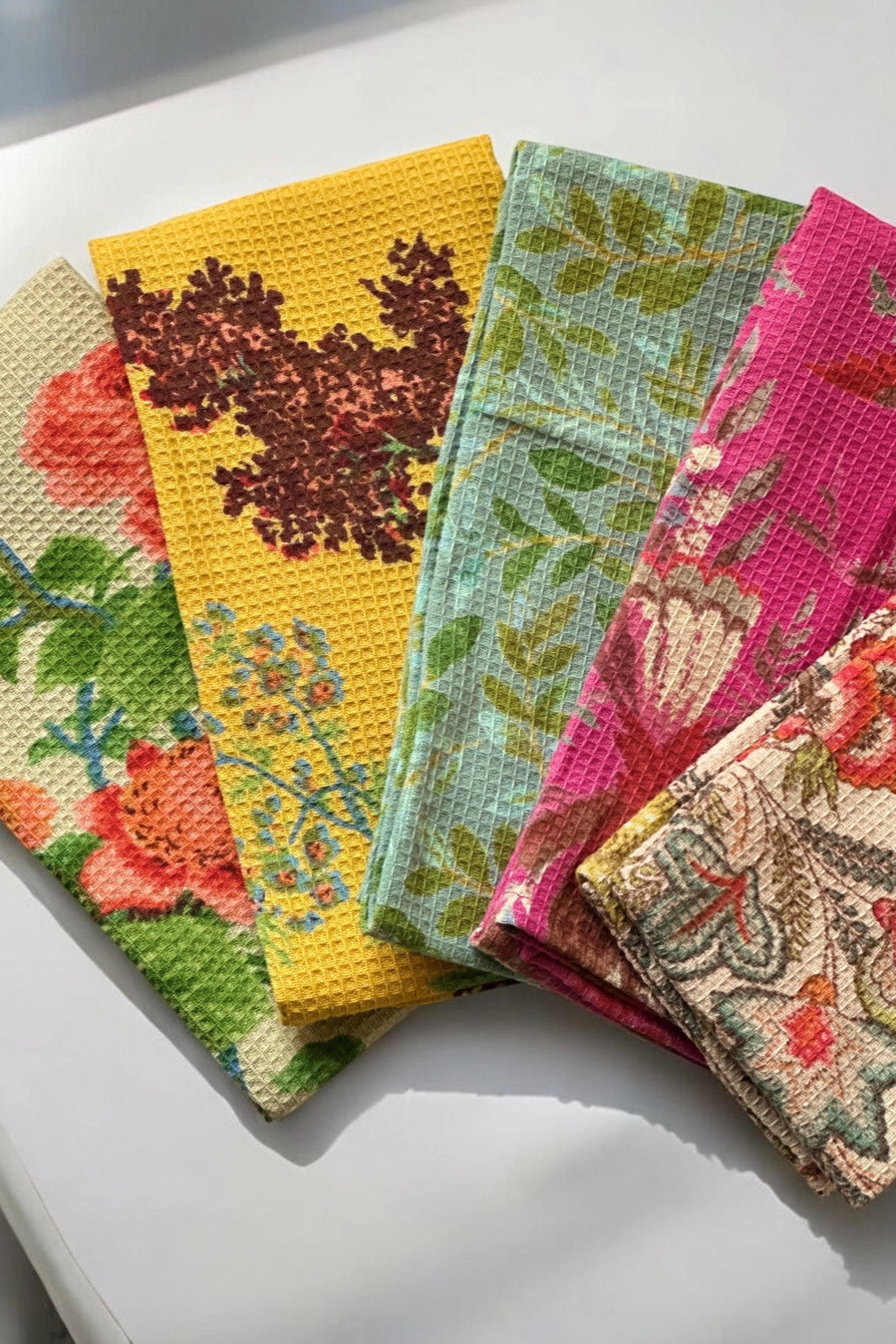 Set of colorful fabric towels with floral patterns on a white surface ©Annahmol