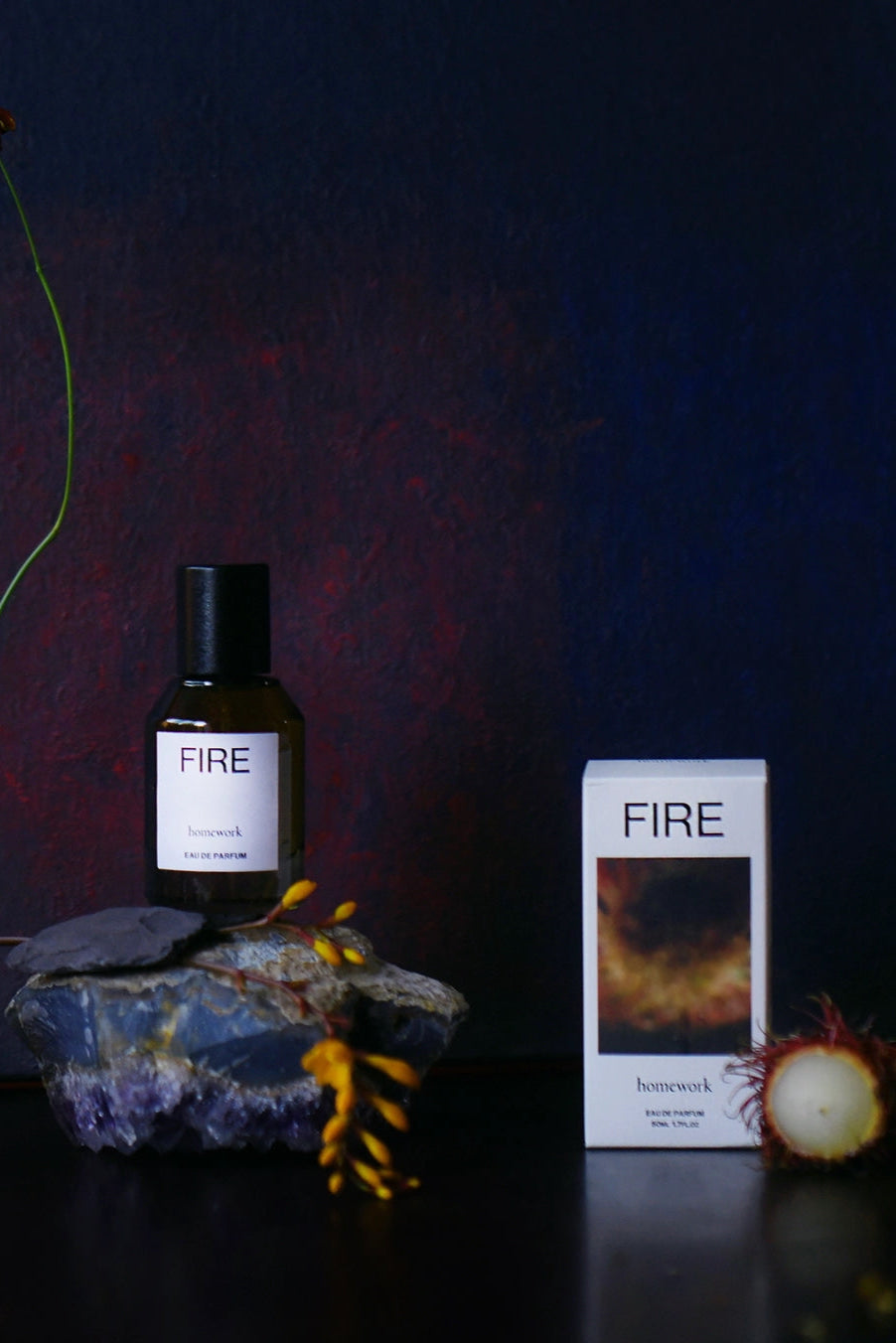 Fire Eau de Parfum FIRE perfume bottle and packaging on a dark background with decorative elements. ©Homework