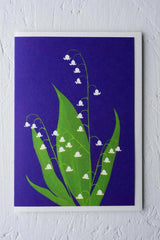 Lilly of the Valley greeting card by Stengun Drawings against a white wall.