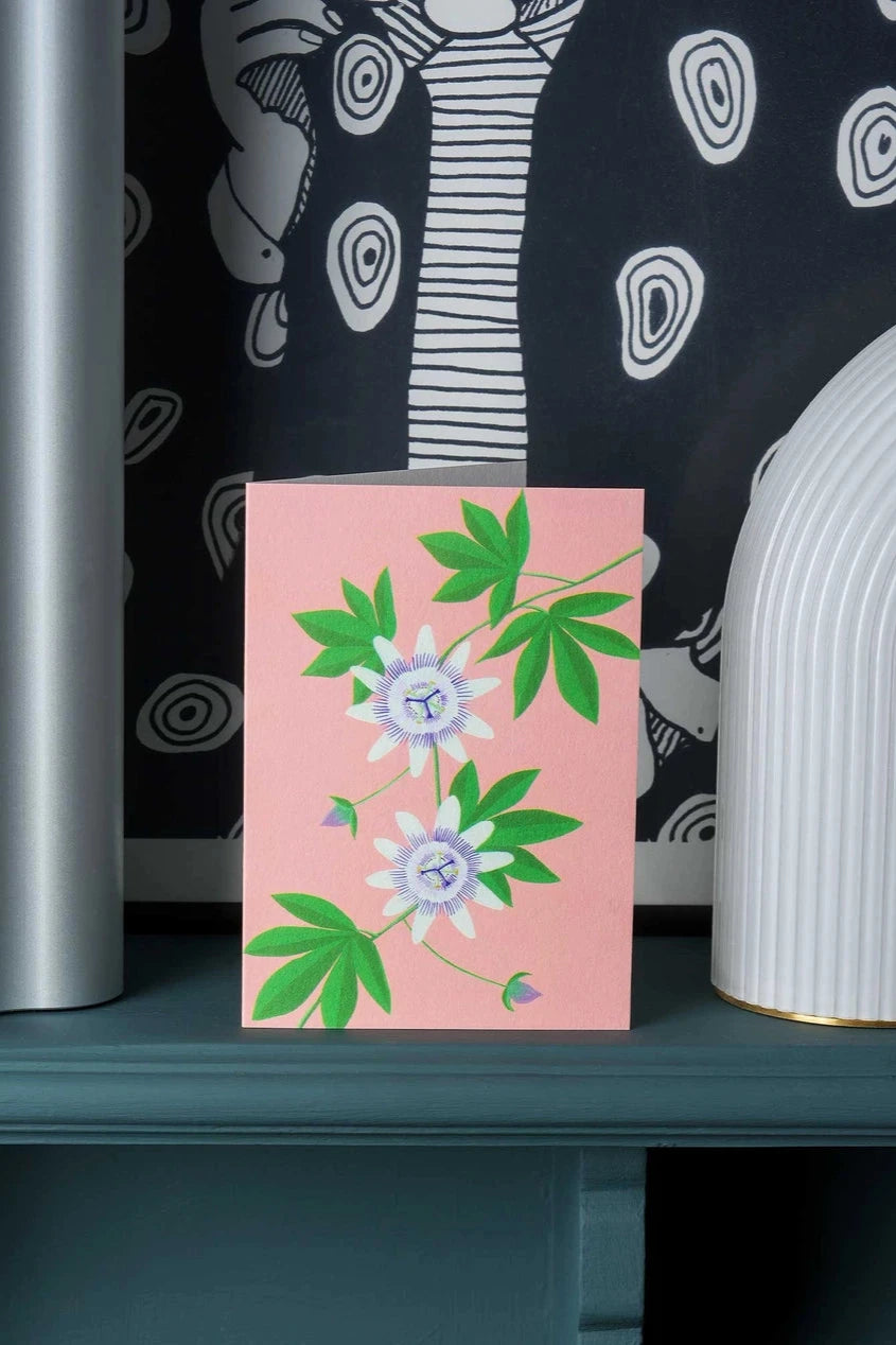 Passion Flower Greeting card by Stengun Drawings  in a lifestyle shot contrasting against the white and black wallpaper