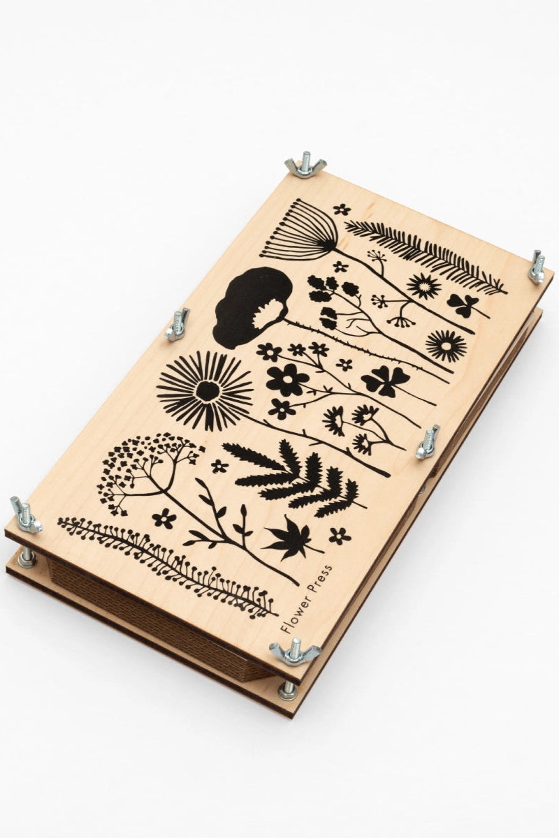 Wooden flower press by Studio Wald with black floral and botanical designs on a white background ©Studio Wald