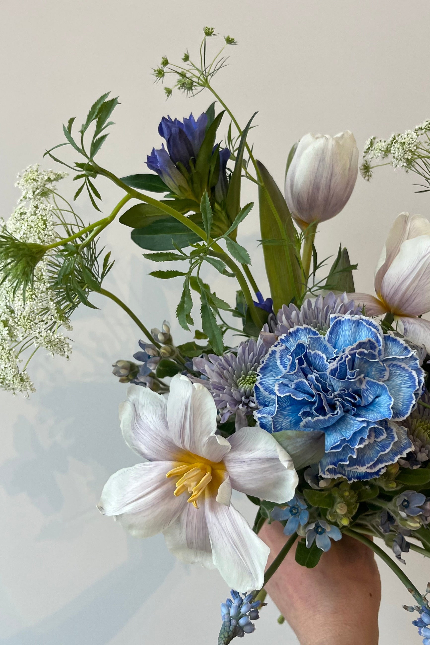 Photo of floral arrangement on a white surface in front of a white wall at Sprout Home. The flowers are various shades of blue, indigo, aqua and teal. ©Sprout Home #size_$75
