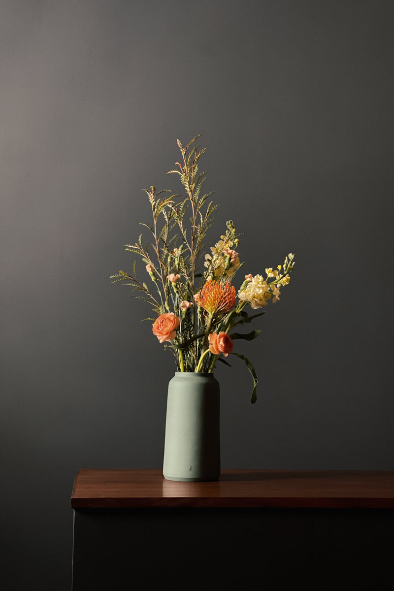 Forest Green bouquet vase with floral inside sitting on a wood credenza by L'Impatience Pottery