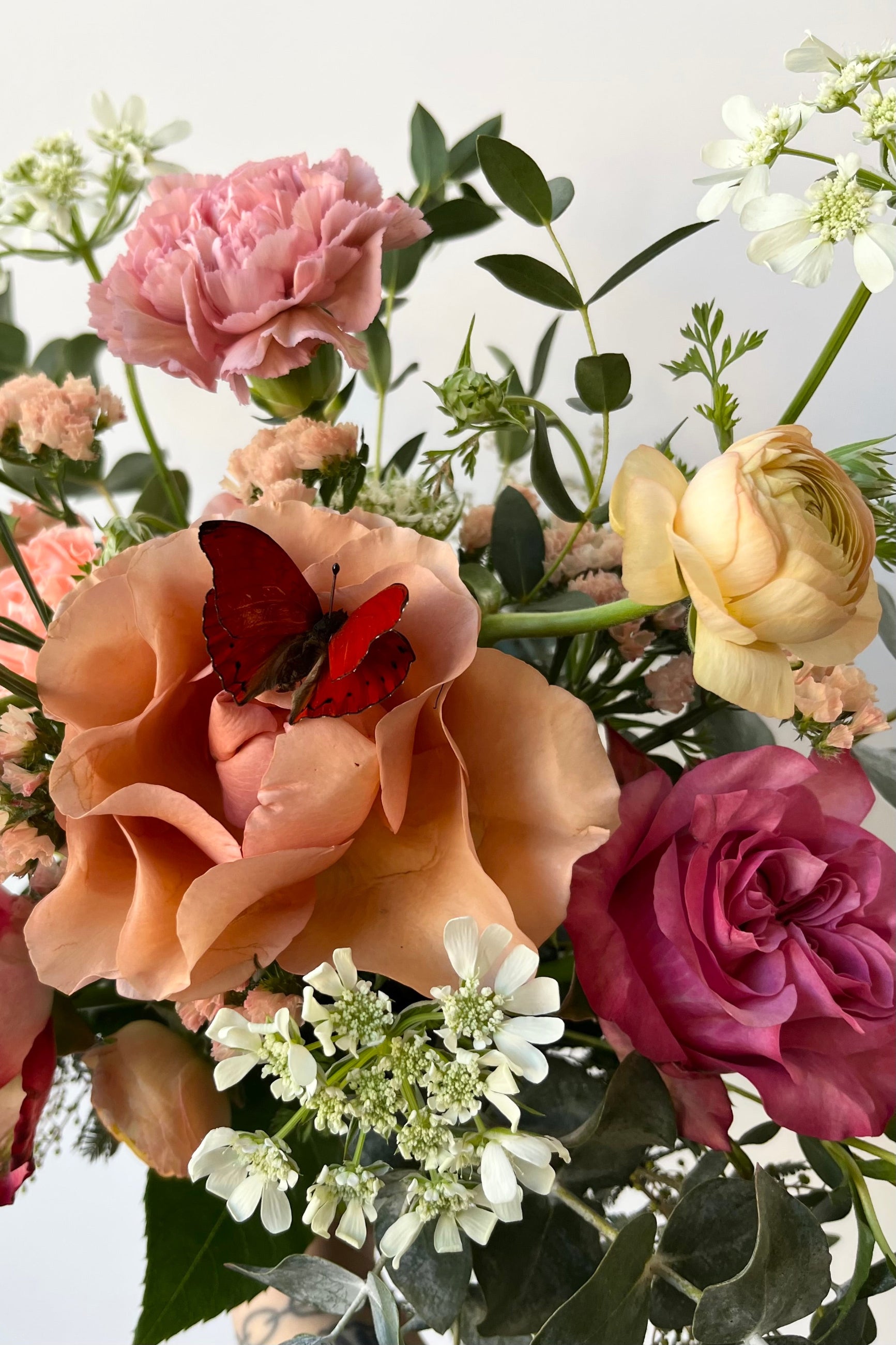 A detail of a custom arrangement by Sprout Home featuring a real butterfly sitting on a warm peach rose ©Sprout Home #size_PLP