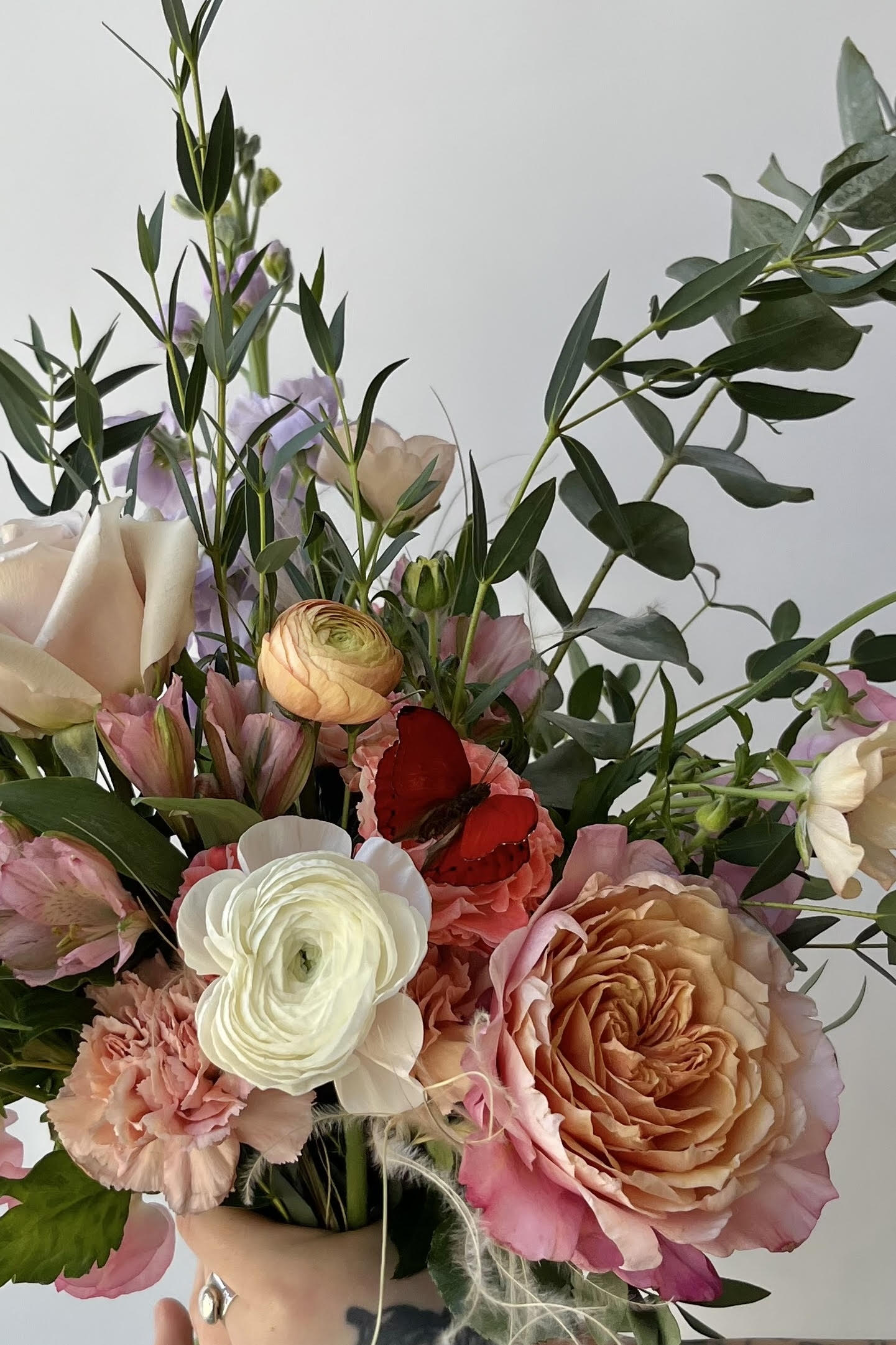 Detail of a custom floral arrangement Butterflies with white Ranunculus and red butterfly ©Sprout Home #size_$130