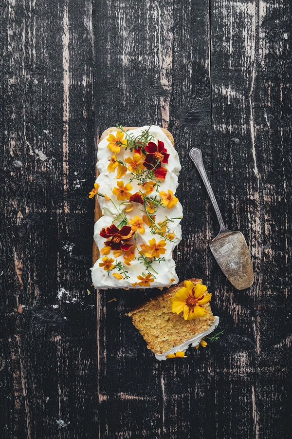 A page from the Flowers on a Plate book showing a yellow and rust colored flowers on a spread on top of a desert loaf.