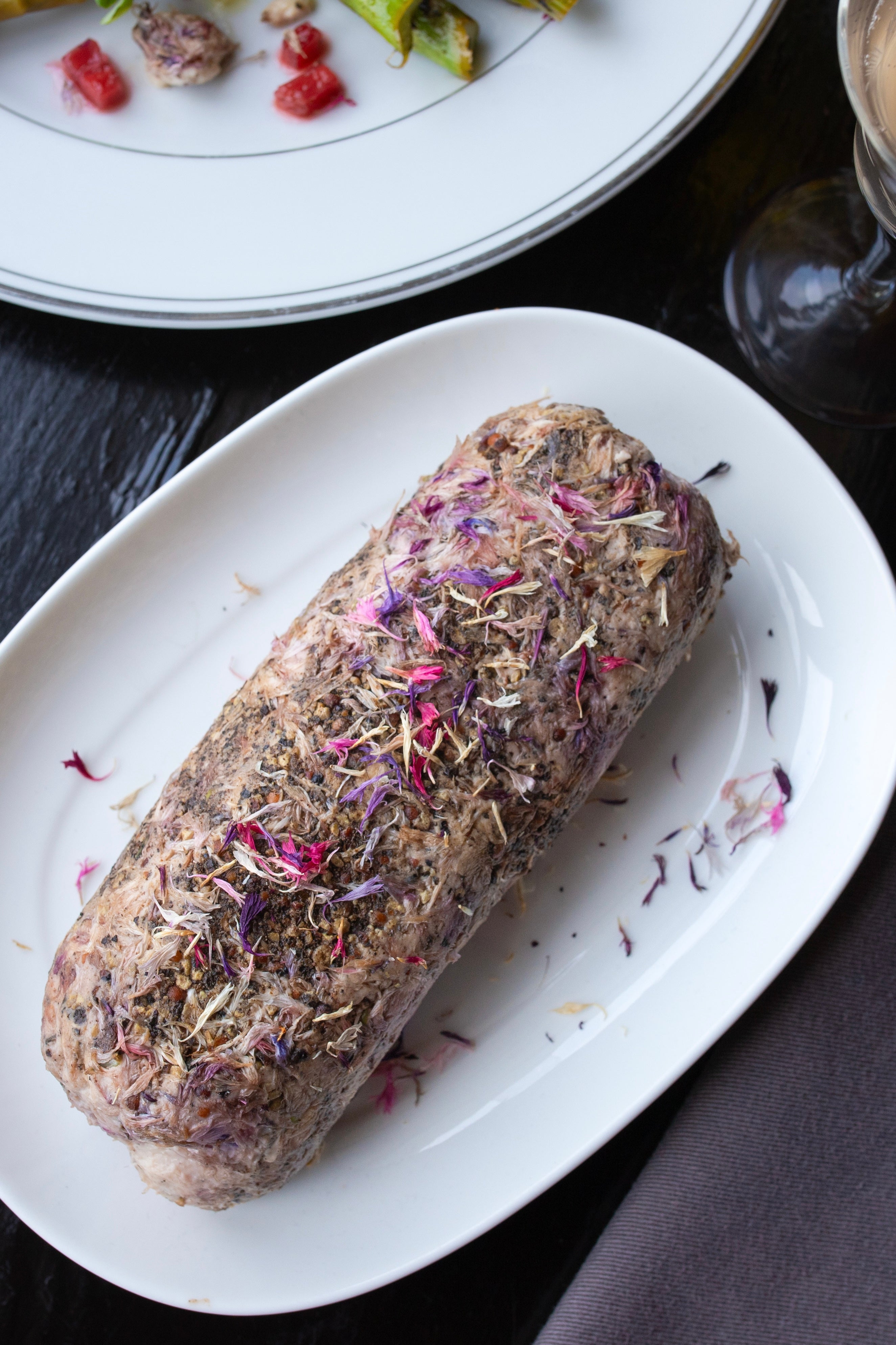 Photo of flower peltals on a dish prepaded on an oval white plate. The photo is by chefs Mateja and Grills at Heritage Restaurant and Caviar Bar.