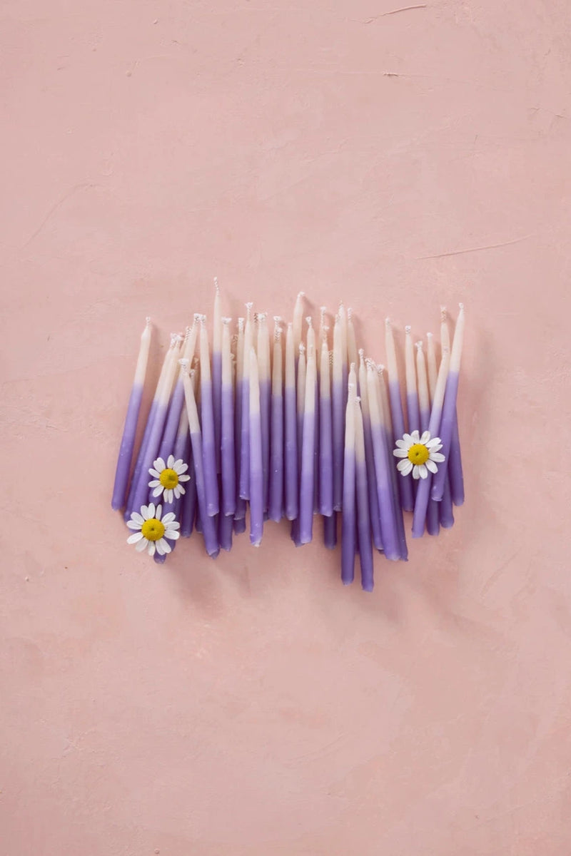 Knot & Bow Short Ombre Violet beeswax candles grouped together with chamomile flowers.