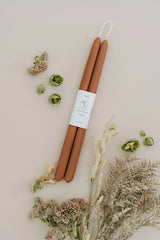 Mo & Co Terra Cotta beeswax taper candles sitting flat surrounded by naturally dried floral.