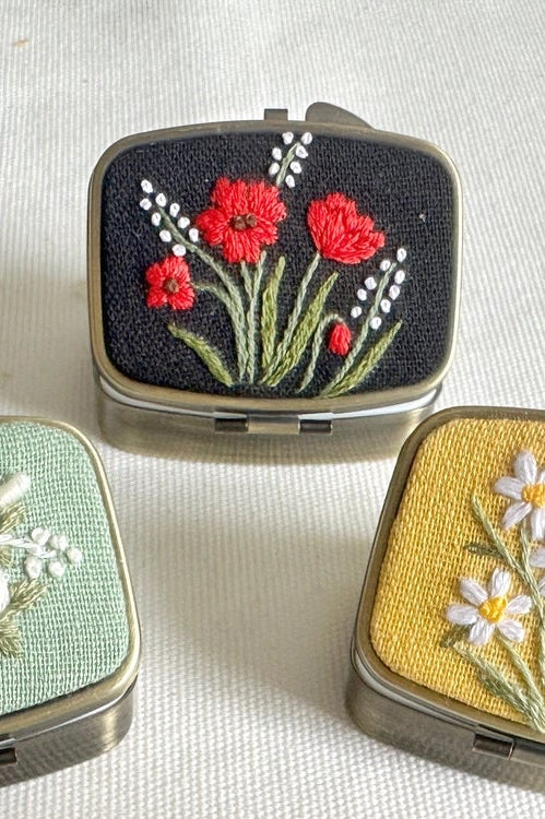 Set of compact mirrors with floral embroidery on a textured surface ©Quince Fables