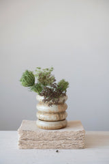 Ribbed stoneware planter with green inside and sitting on a pile of pressed paper.