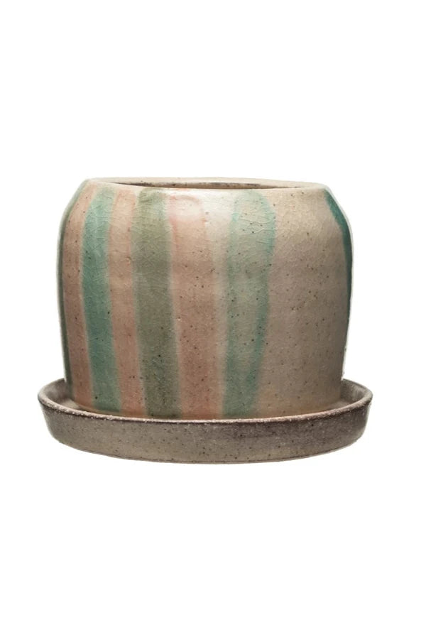 The striped terracotta planter shown from the side with its blue green and pink handprinted stripes.