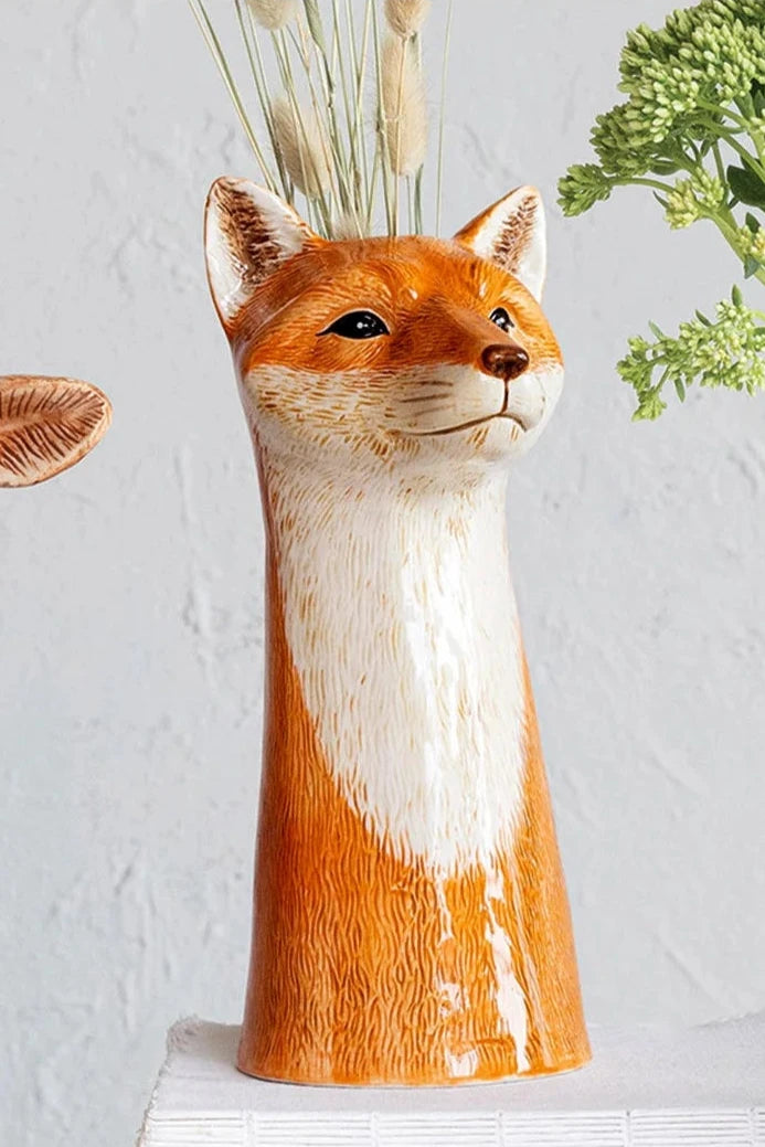 Fox vase with natural bunny tails inside and on a white surface