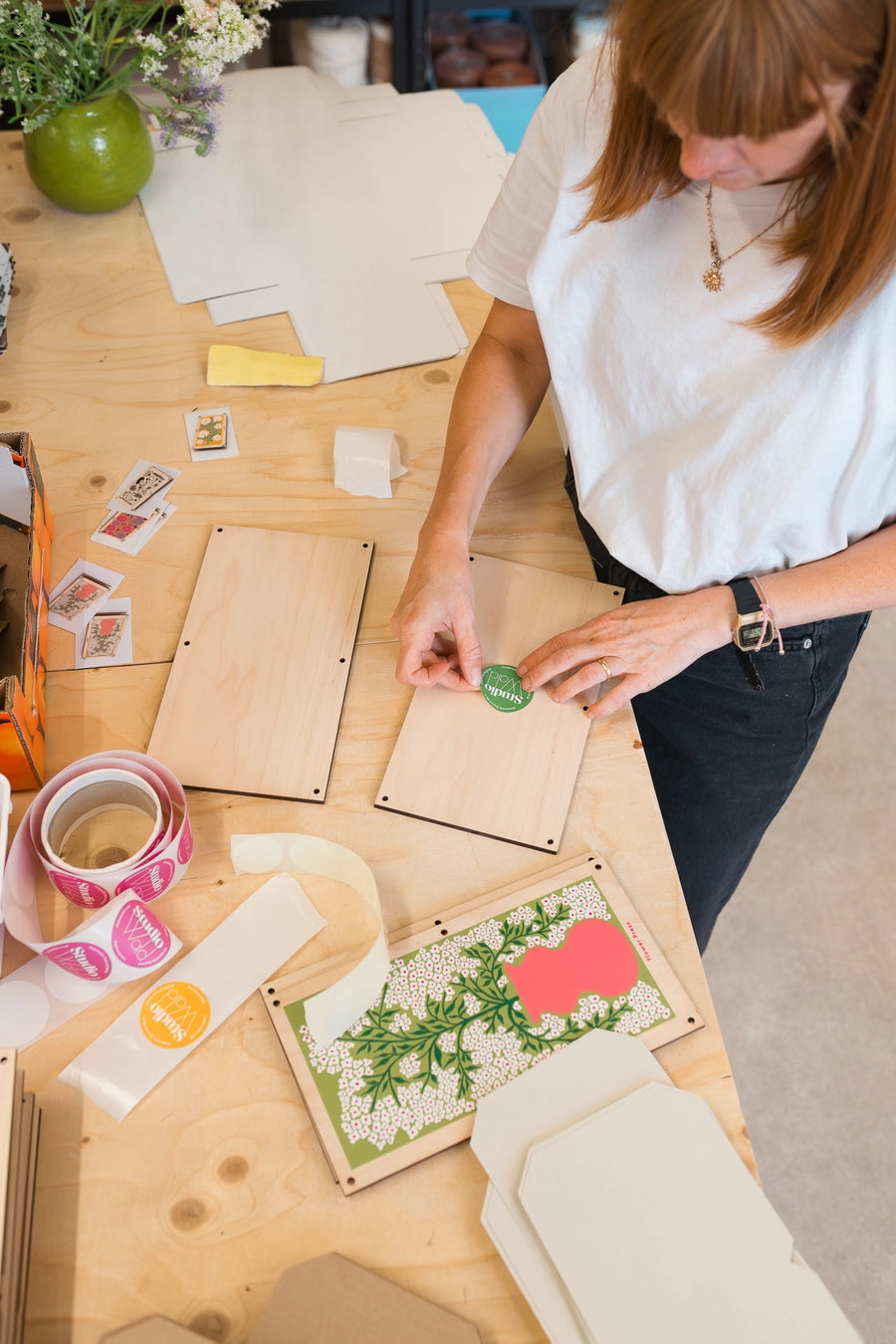 Person working on a craft project with wooden boards and decorative items on a table assembling the Forget Me Not flower press ©Studio Wald