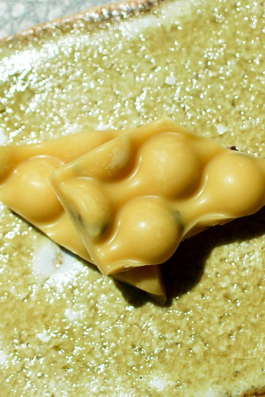 a piece of Passionfruit Chocolate Bar with a textured surface on a matching plate ©Deux Cranes