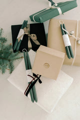 Mo & Co beeswax taper candles in Forest Green various sets mixed with wrapped presents.