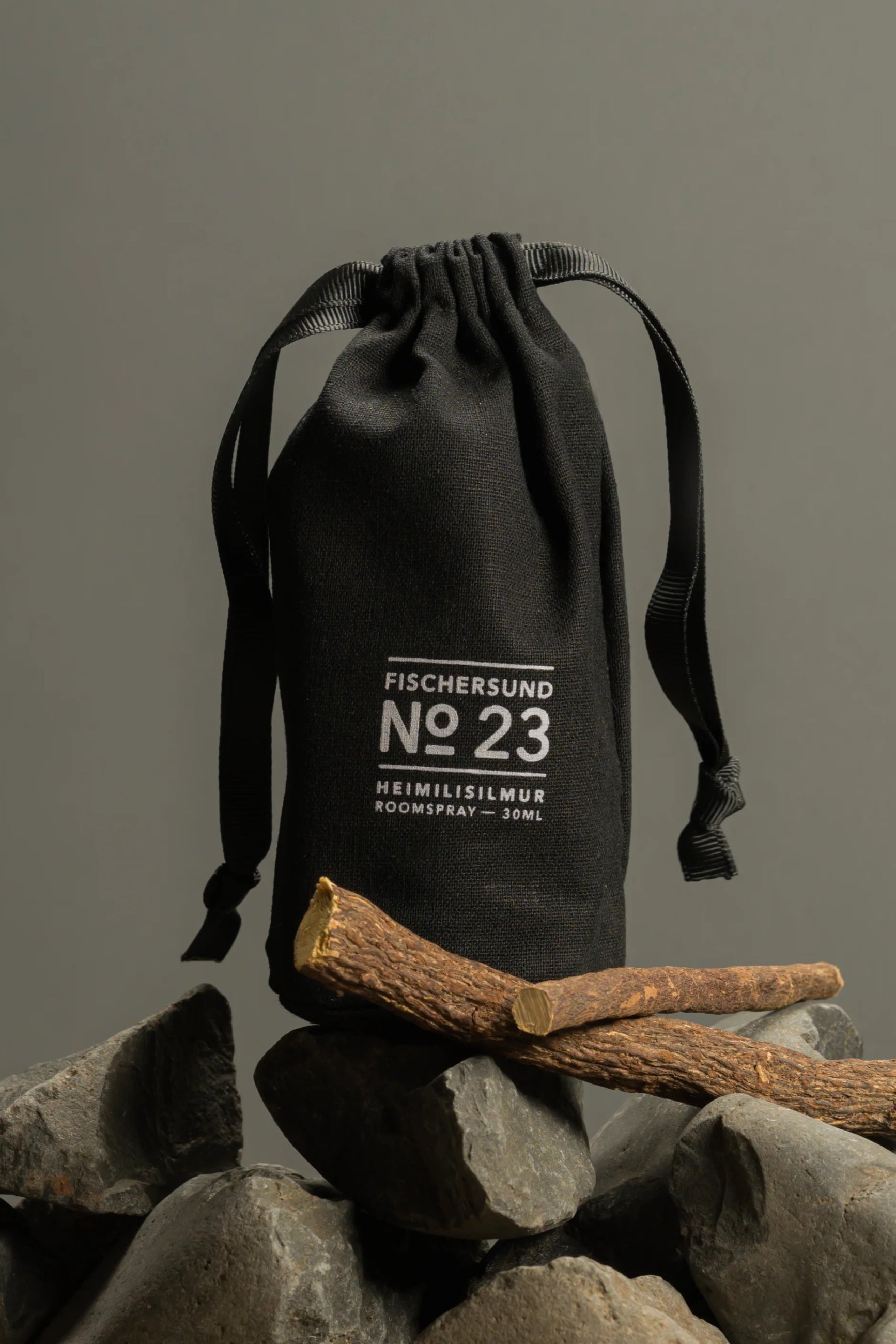 Black drawstring bag with 'Fischersund No 23' text on rocks and sticks against a gray background ©Fischersund
