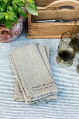 A set of Natural Linen Napkins staked on a table in a lifestyle shot by Fog Linen Work.