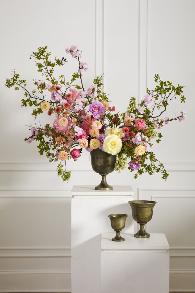 Floral arrangement in a decorative Hullen vase on a white pedestal against a white wall. ©Accent Decor