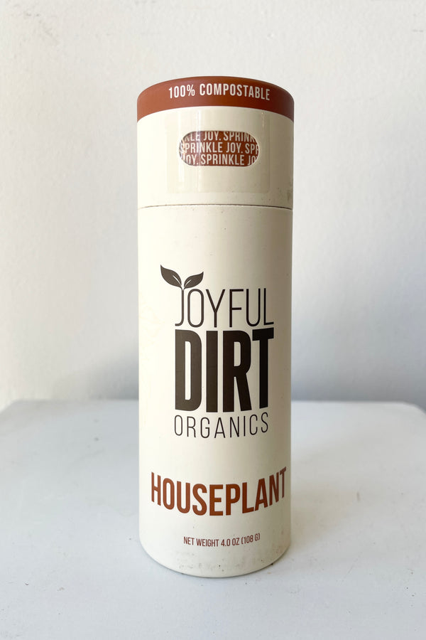 Joyful Dirt Houseplant fetilizer display tube against a white wall. 