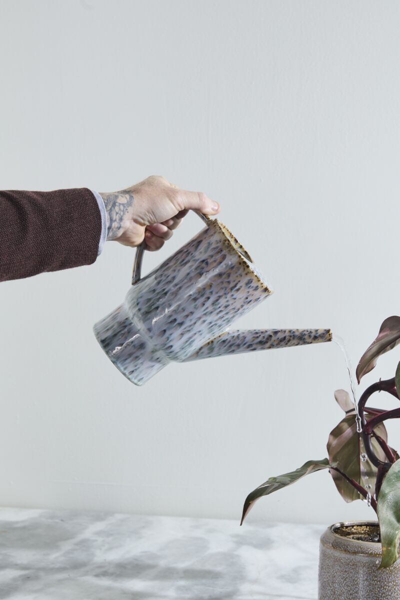 Person watering a plant with a marble-patterned Lucien watering can against a light background ©Accent Decor