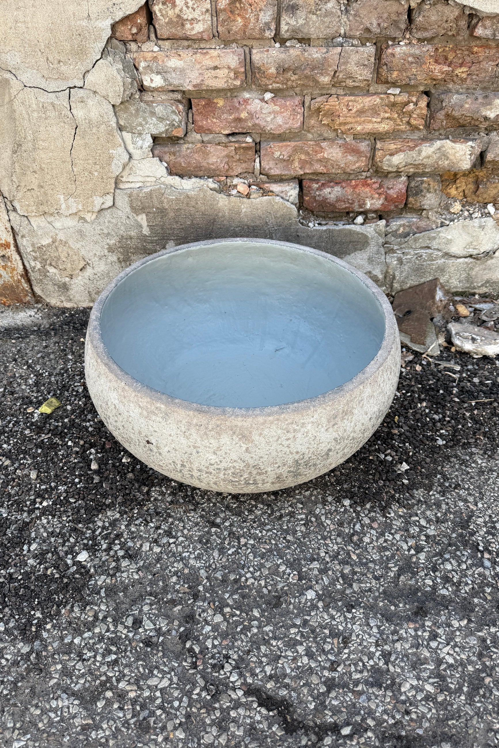Low Ficonstone Greige Low Bowl Large against a stone wall background ©Sprout Home