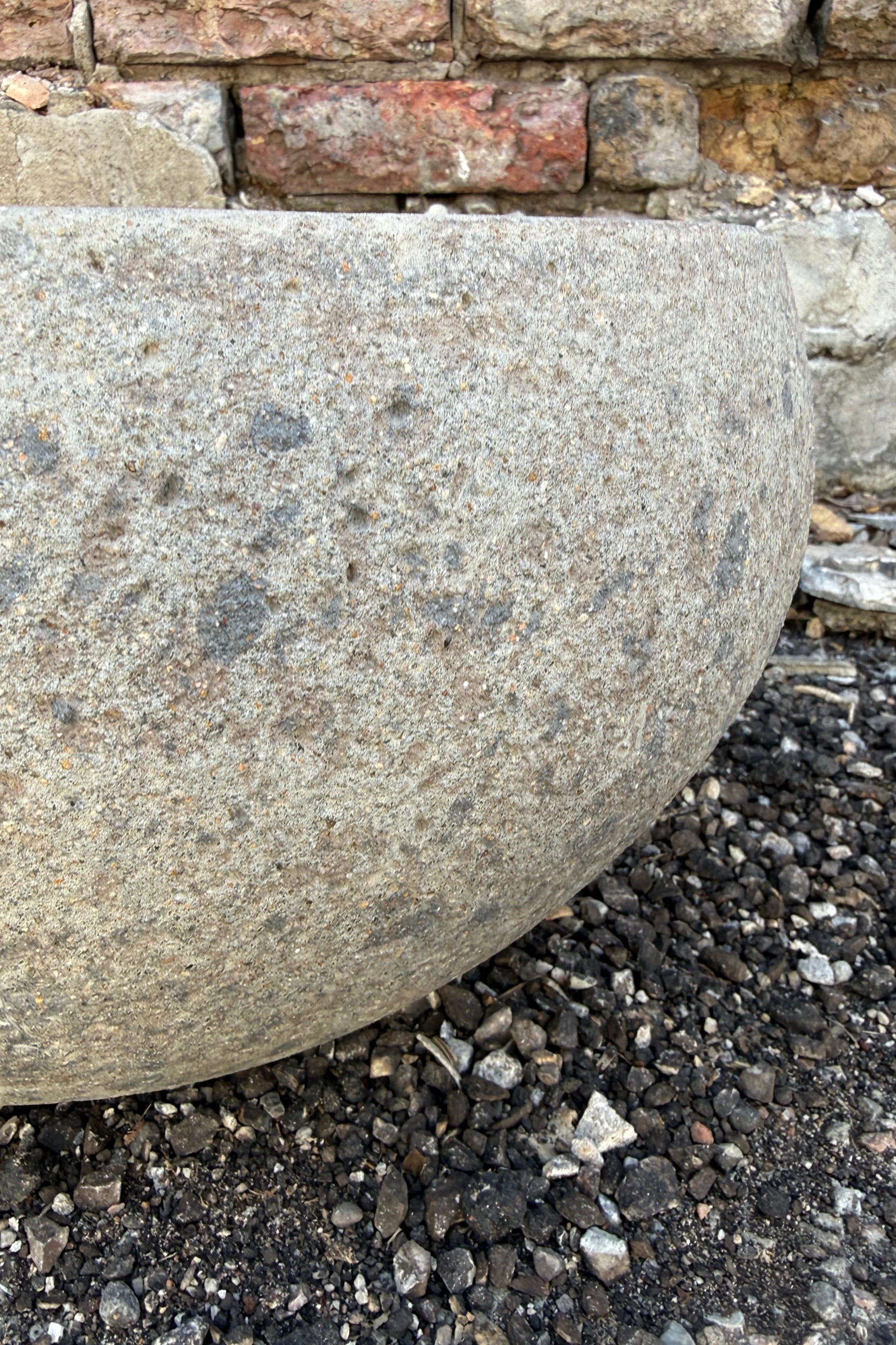 Close-up of a Low Ficonstone Greige Low Bowl Medium on a gravel surface with a brick wall in the background ©Sprout Home
