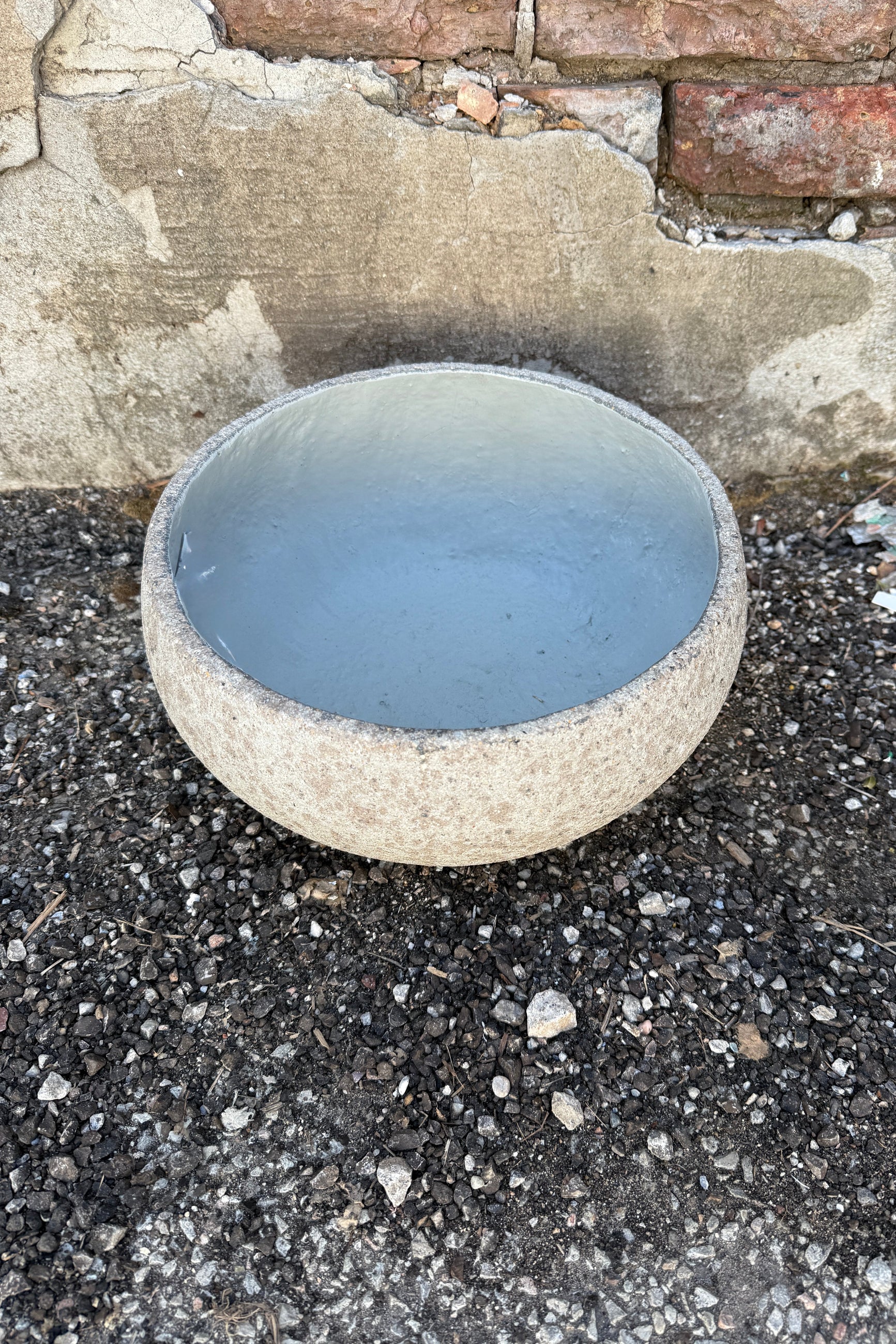 Low Ficonstone Greige Bowl Small with a smooth finish on a gravel surface. ©Sprout Home